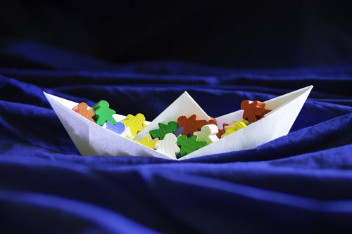 Immigration emigration migration concept, paperboat with meeples