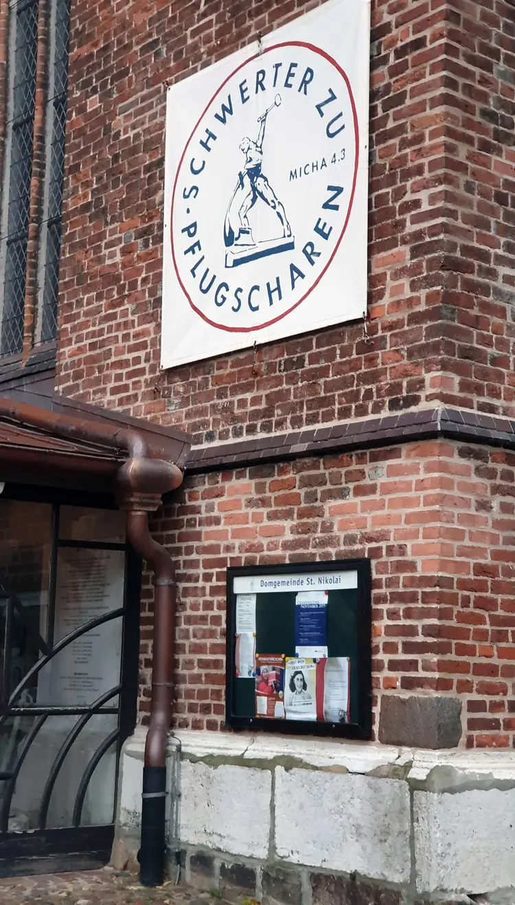 Selbst 30 Jahre nach der Wende hängt am Eingang des Greifswalder Doms noch ein Transparent mit dem Motto der einstigen DDR-Friedensbewegung: „Schwerter zu Pflugscharen.“