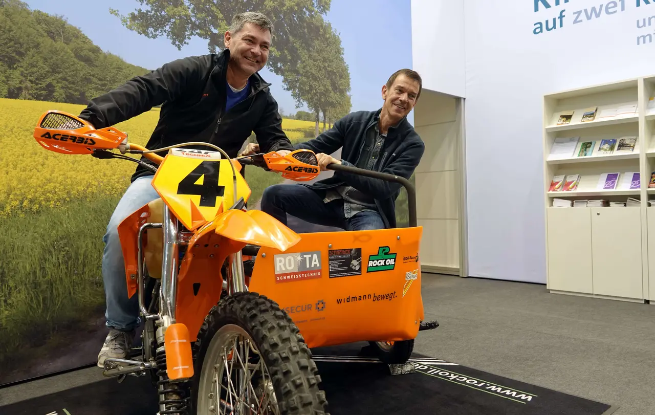 Auch Große haben ihren Spaß auf dem Motocross-Gespann: Roland Hahn (l.) und Norbert Günther aus Wimsheim (Enzkreis) bestiegen das Seitenwagen-Motocross-Gespann der früheren Vizeweltmeister Klaus und Thomas Weinmann am Stand der Kirchen auf der CMT.
