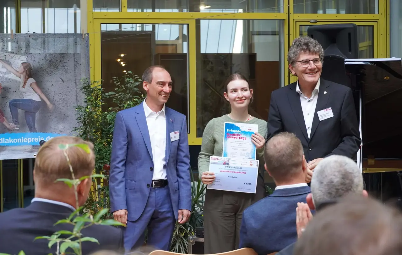 Landesjugendpfarrer Matthias Rumm (links) und Landesbischof Ernst-Wilhelm Gohl (rechts) gratulieren Julia Lofink.