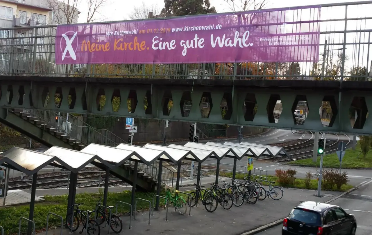 Groß, violett und kaum zu übersehen: Mit acht großen Werbebannern über den Haupteinfallstraßen Stuttgarts macht die Evangelische Landeskirche in Württemberg seit Montag auf die Kirchenwahl am Sonntag, 1. Dezember, aufmerksam.
