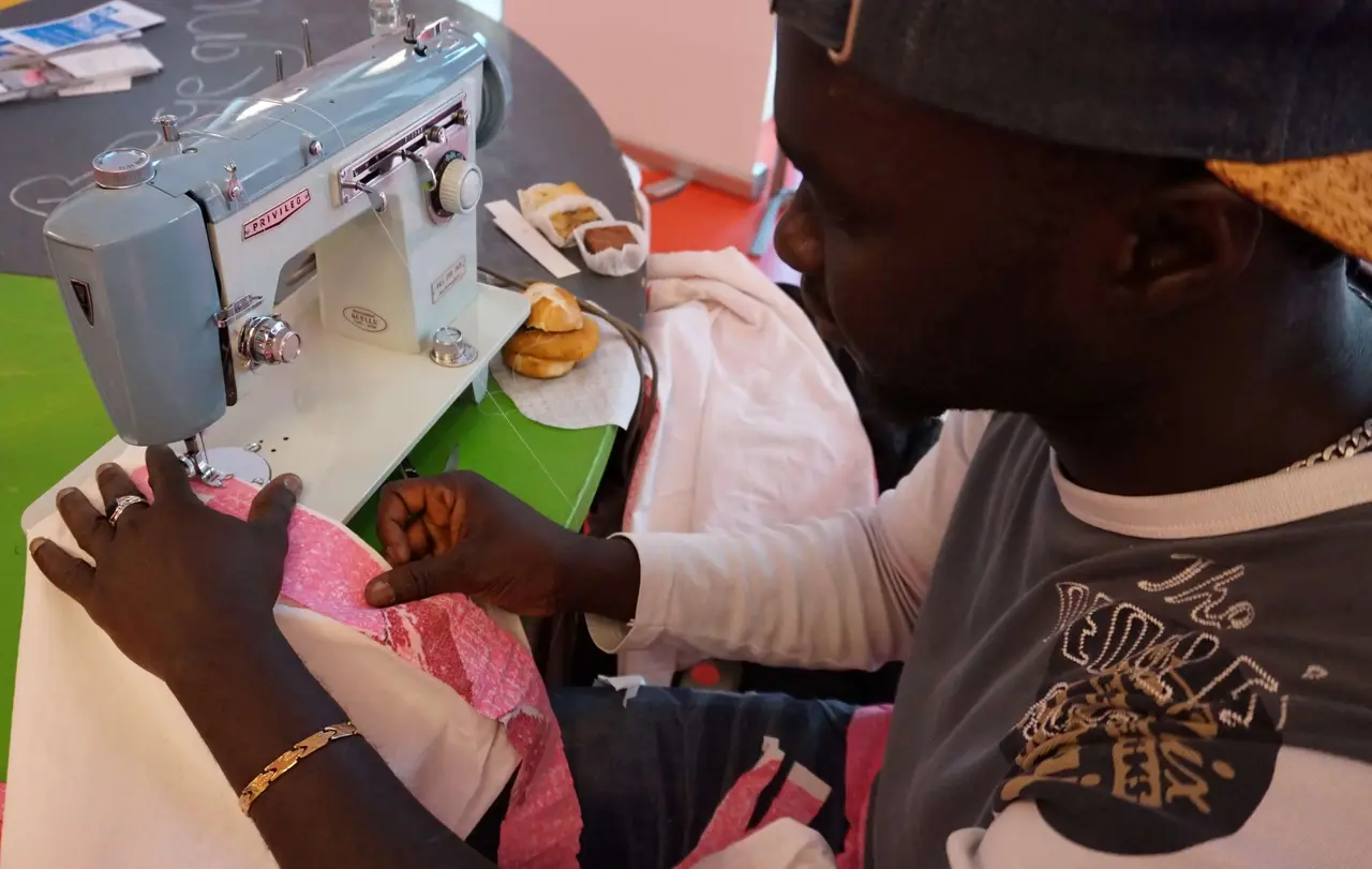 Alajie, aus Gambia geflohen, näht aus Stoffresten Kleidung, die später im Diakonieladen angeboten wird