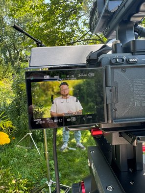 Kamera auf Stativ im Garten, in deren Bildschirm Tobias Wörner zu sehen ist