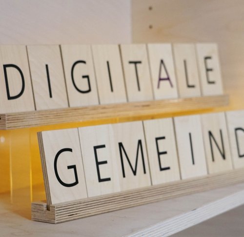 Das Bild zeigt Holzbuchstaben, die den Text "Digitale Gemeinde" formen.