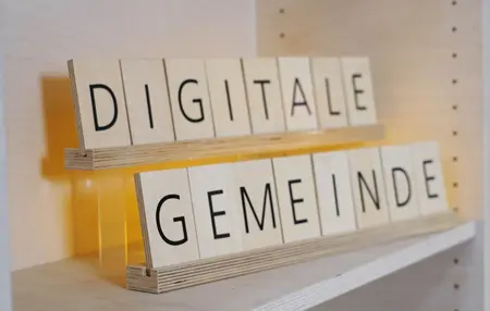 Das Bild zeigt Holzbuchstaben, die den Text "Digitale Gemeinde" formen.