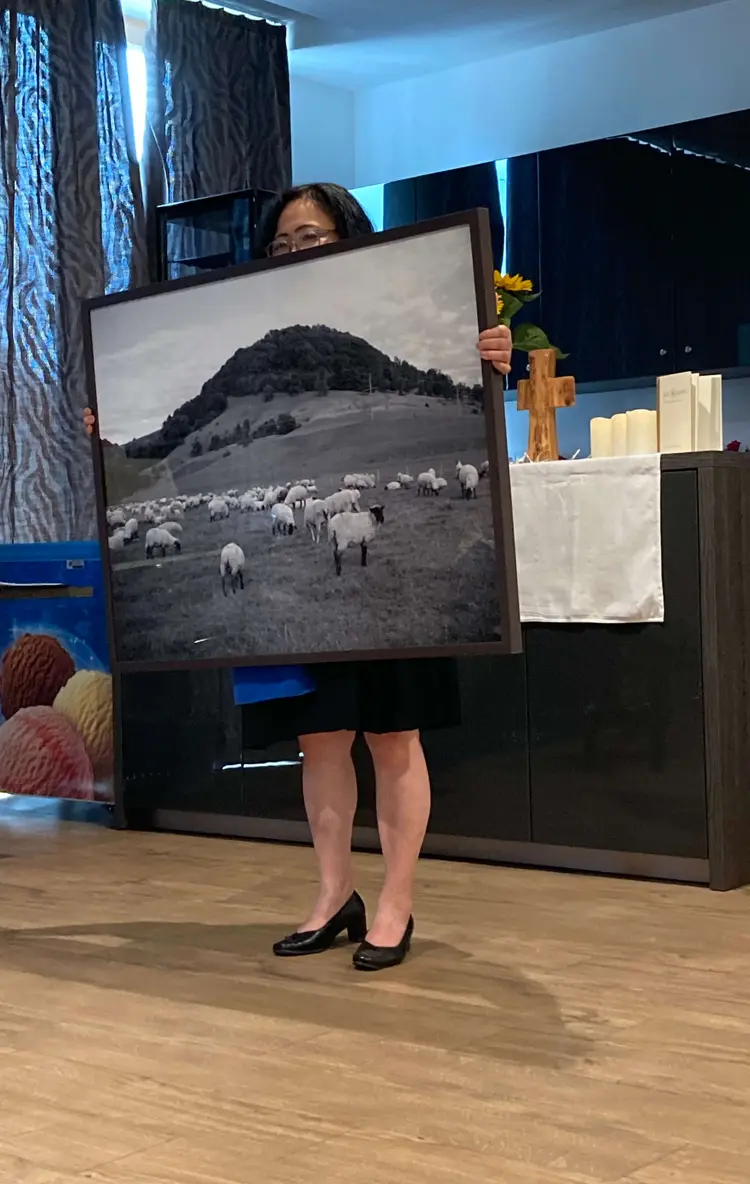 Yuka Suzuki-Winkler hält ein Foto einer Schafweide in die Höhe. Wichtig ist es, Symbole einzusetzen und die Sinne anzusprechen.