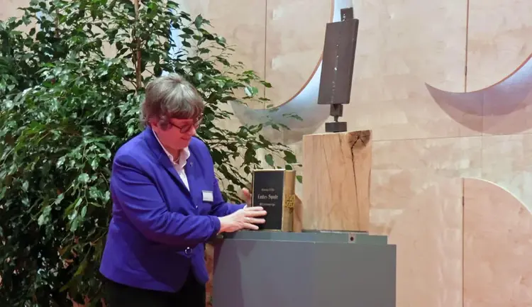 Synodalpräsidentin Schneider legt die Bibel zum Kreuz, das für die Synode angefertigt wurde.